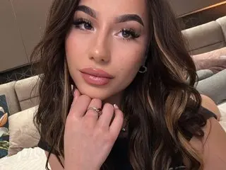 AlissiaRilley poses for a close-up headshot, showing her long wavy brown hair and clear skin or makeup.