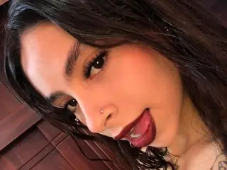 AmbeerRosse smiles playfully with her tongue out, showing her dark hair and makeup in a close-up selfie.