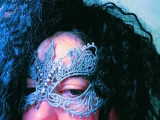 AmberCrystalZone wears a silver lace mask over her eyes, framing her dark, curly hair and face.