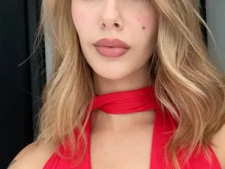 AmeAlcaraz looks into the camera wearing a red halter top with her blonde hair flowing down her shoulders.