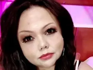 Amputee_woman looks directly at the camera with long dark hair and red lipstick.