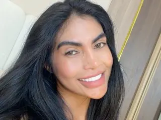 Smiling brunette woman with long dark hair posing for a bright indoor selfie.