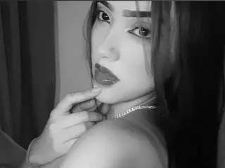 Angel_kiss_18 looks directly at the camera with long dark hair and a close-up view of her face and neck in this black and white photo.