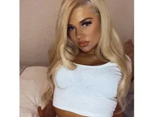 Angellxoxo poses in a white crop top with her long blonde hair flowing over her shoulders.