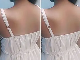 AnishaBeauti shows her bare back and shoulders, wearing a white strap top or chemise, with her dark hair pulled up.