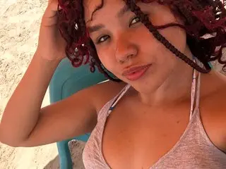 Young woman with red curly hair in a grey bikini relaxing on a sunny beach.