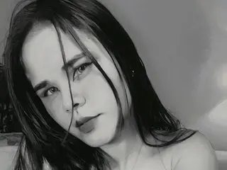 AnniieSmith25 poses with long dark hair and a direct gaze, showing her bare shoulders and neck in a close-up black and white portrait.