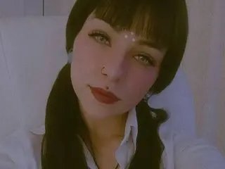 Annyleytonnn poses with a direct gaze, showing her face, dark hair with bangs, and a white shirt against a plain background.