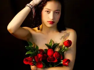 Beautiful woman with dark hair holding a bouquet of red roses against a dark background for a romantic mood.