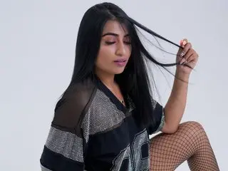 AntoniaRoss poses with her long black hair while wearing a black mesh top and fishnet stockings.