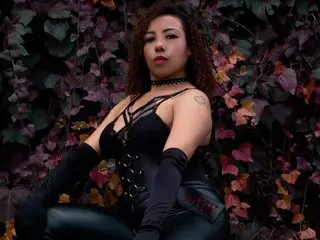AryFox89 poses in black lace lingerie and black gloves, showing her dark hair and neck against a background of dark red leaves.