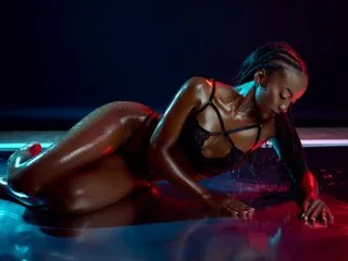 AshleyFerri reclines in a dark pool wearing black lace lingerie with her wet skin glistening under red and blue lights.