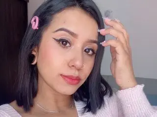 Ashleymayer199 poses for a selfie with her dark hair and winged eyeliner, wearing a pink sweater.