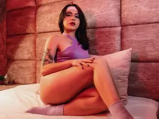 AtheneaVoss poses naked on a bed, showing her bare breasts and legs while wearing a purple bra and light purple socks.