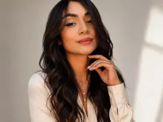 AuroraPonce poses with her long dark hair and a soft smile, wearing a light-colored top against a plain background.