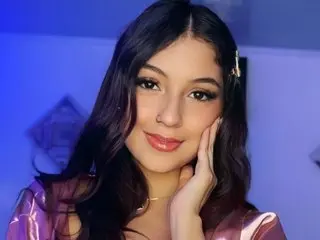 AveryCobb poses with her hand against her cheek, showing her long dark hair and soft smile against a blue background.