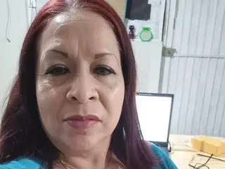 AzulVioleta looks directly at the camera with her long, dark red hair framing her face in a close-up shot.