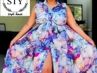 Curvy woman in a vibrant blue and purple floral maxi dress posing in a bright indoor setting.