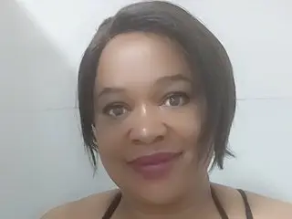 BUSTYQUEEN30 looks at the camera with a smile, wearing a black top with her dark hair styled down.