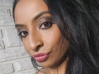 BabeXX69XX looks directly at the camera with long black hair and dark eyes, posing close-up against a white brick wall.