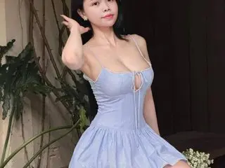 Beally079 poses in a light blue cutout dress, showing her cleavage and shoulders with her dark hair styled back.