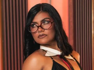 BellaContreras looks directly at the camera with a serious expression, wearing a black top and her dark hair styled straight.