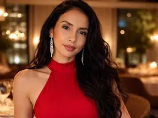 Elegant woman in a red halter dress and silver earrings posing in a warm, dimly lit upscale restaurant.
