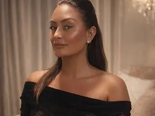 Bellamay95 poses with a direct gaze, wearing a black off-the-shoulder top with her dark hair pulled back.