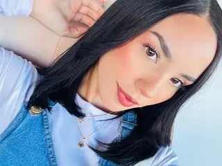 Bellywrist poses close-up, looking at the camera with long black hair and a light blue shirt.