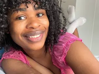 Bestplay smiling at the camera while wearing a pink ruffled top and laying down.