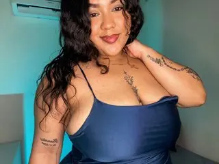 BettyBoobK poses with her long dark hair, wearing a blue tank top that shows off her cleavage and shoulders.