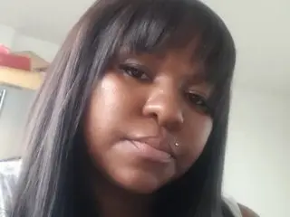 BigBlackClitxx looks into the camera with a close-up selfie shot, showing her long dark hair and facial features.