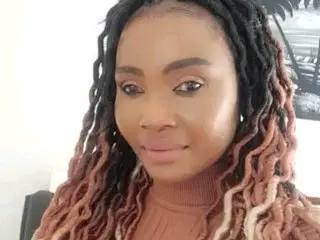 BigButtGodess66 poses close-up, showing her face and long, reddish-brown dreadlocks while wearing a brown turtleneck top.