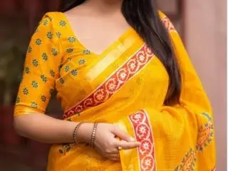 Bisakha wears a bright yellow patterned blouse and matching saree, posing with her hands resting near her waist.