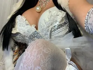 Woman in elegant white lace corset and pearl necklace wearing a glamorous bridal or fantasy costume.