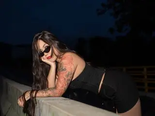 BlairColins poses outdoors at night, wearing a black top and showing her long dark hair and tanned skin.