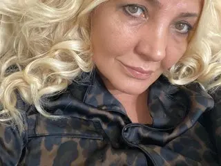 Blondyy poses close-up, wearing a dark leopard print top with her blonde hair styled in loose curls.