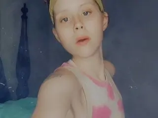 BreezyBree95 poses in a pink and white patterned tank top, looking directly at the camera with her blonde hair pulled back.