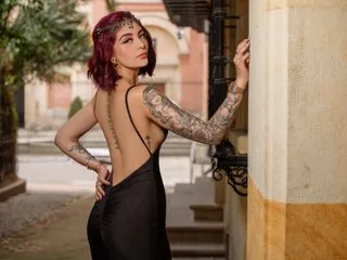 BrianaWells poses outdoors in a backless black dress, showing off her tattoos and red hair.