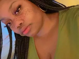 BrielleBarbie looks into the camera with long dark braids and a green top.