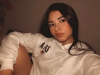BrissleyLancaster poses in a white long-sleeve sweatshirt, looking at the camera with her long dark hair down.