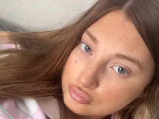 BritishBeckyXX with long brown hair looking directly at the camera in a close-up headshot.