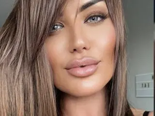 BritishMissCharmaine poses for a close-up headshot, showing her long brown hair and light eyes while looking directly at the camera.
