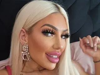 BritishTastyCherryxo smiles at the camera with long blonde hair and large gold earrings.