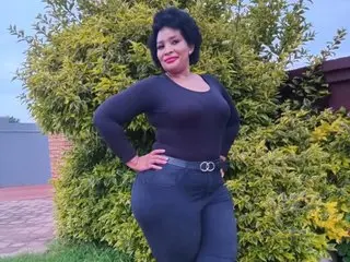BustyBBWs poses outdoors with her hands on her hips, wearing a tight black long-sleeved top and black pants, showing off her curves and dark hair.