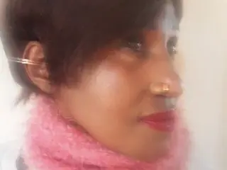 CARAMELBOOTY30 shows her face and dark hair while wearing a pink fuzzy scarf or collar against a plain background.