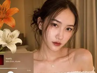 CalyKel poses with a soft gaze, showing her bare shoulders and neck, with her dark hair styled in a loose bun.