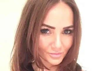 CamiXO looks directly at the camera with her long brown hair framing her face in a close-up headshot.