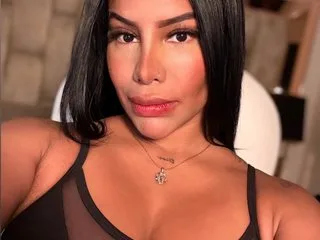 CamilaGonzalezz poses close-up, wearing a black mesh top that shows her cleavage and skin.