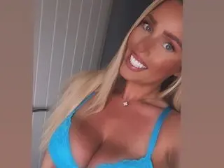 CandyKay25 poses in a blue tank top, showing off her cleavage and blonde hair against a neutral background.